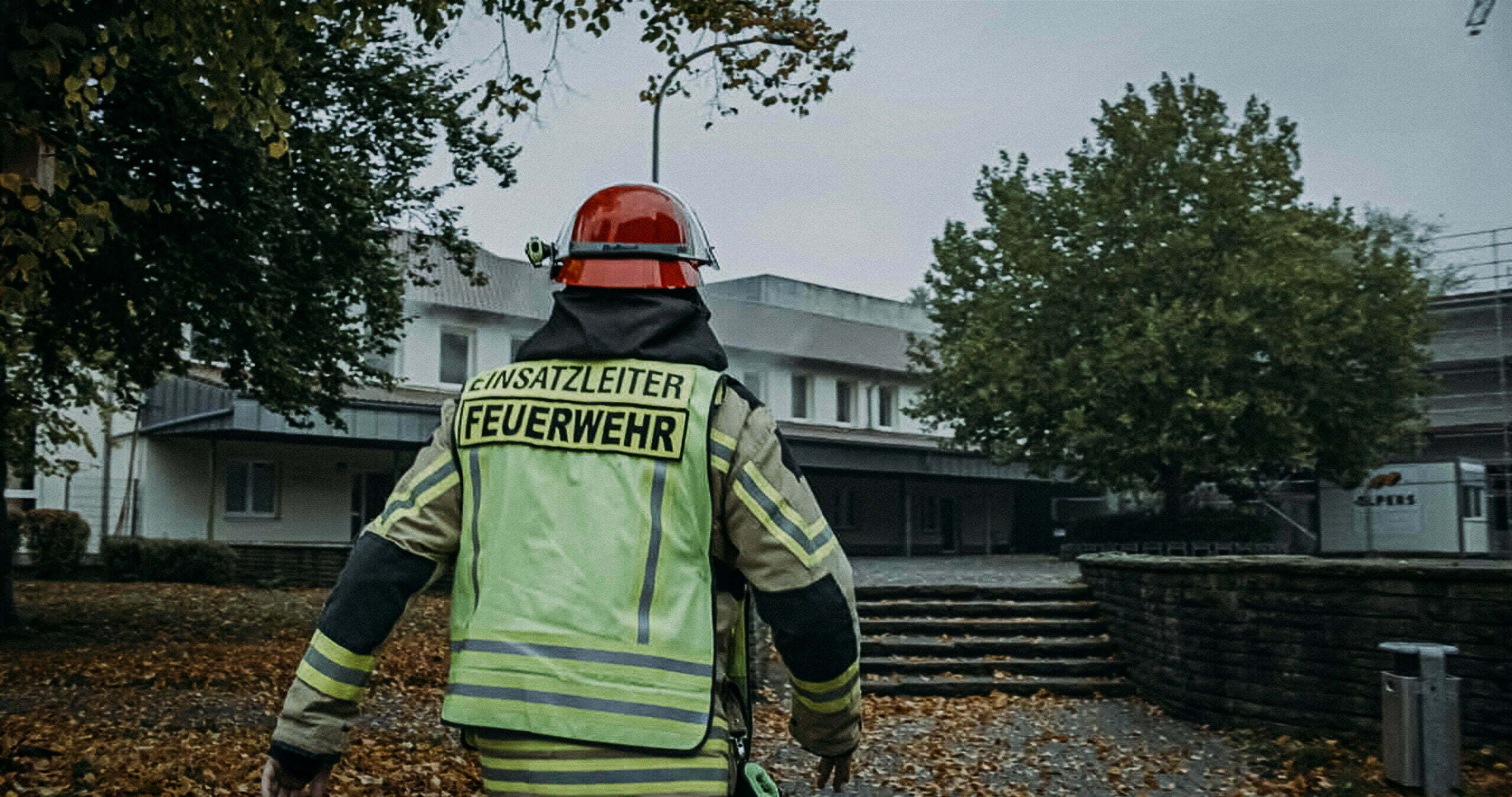 Einsatzleiter in Einsatzkleidung vor Gebäude